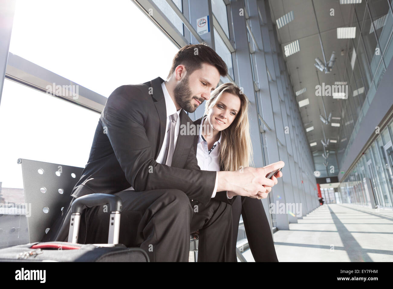 Business partners in airport looking at smart phone Stock Photo