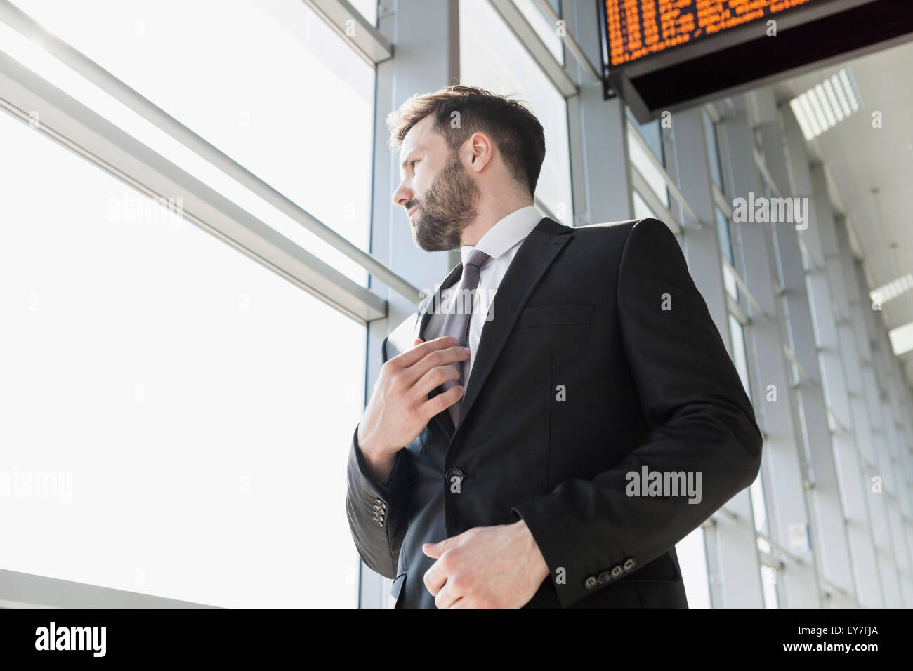 Businessman adjusting tie in airport Stock Photo