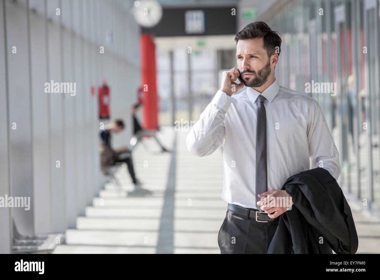 Businessman using phone in modern lobby Stock Photo