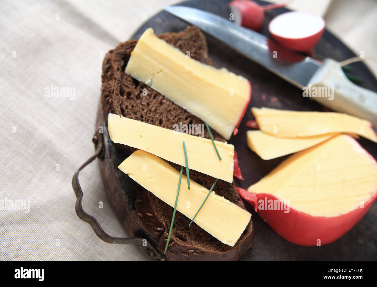Slices of Gouda cheese with dark bread and chives on cutting board with room for text Stock Photo