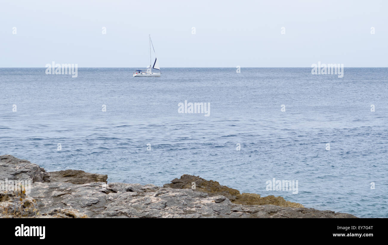 Sailboat on the Sea with Rocky Coast Stock Photo