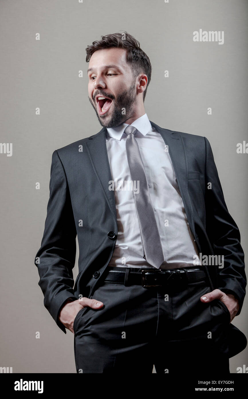 Businessman with hands in pockets mouth open Stock Photo Alamy