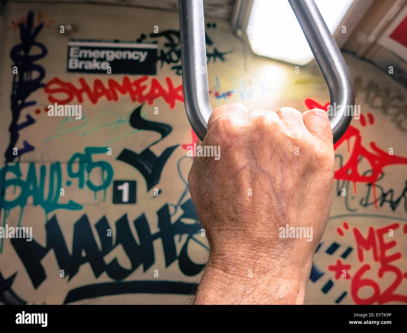 Man's hand holding a pivoted grab handle on a New York City vintage subway. Stock Photo
