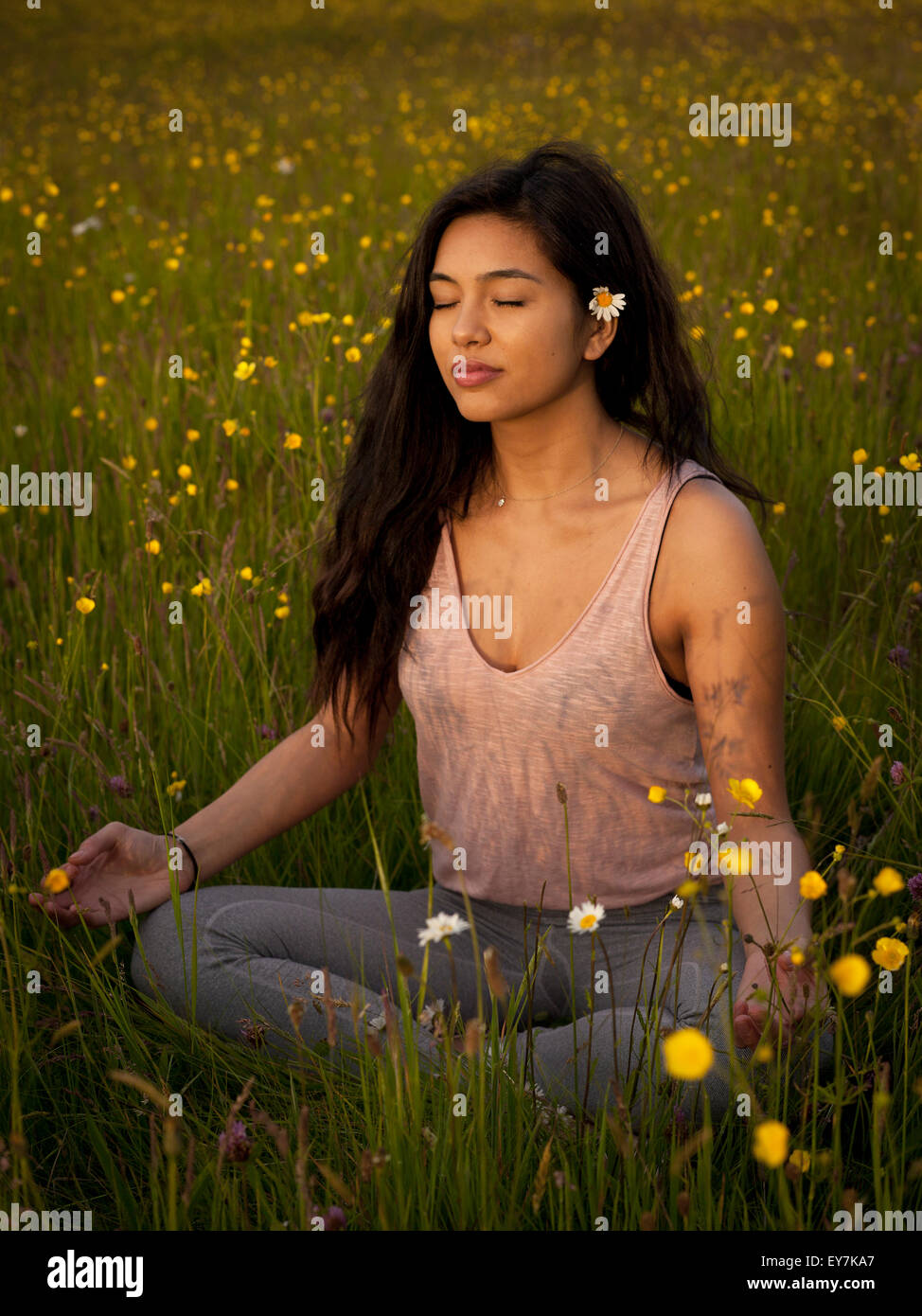 Girl meditating in a wild flower meadow Stock Photo