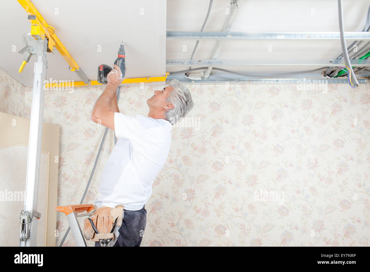 Handyman drilling into the ceiling Stock Photo