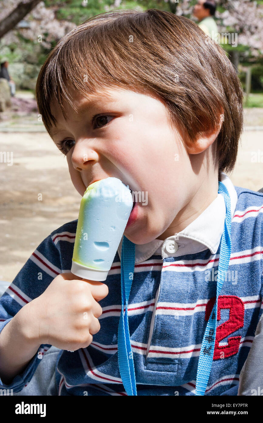 Young Child Boy 3 4 Year Old Biting Into A Light Green And Blue Stock Photo Alamy