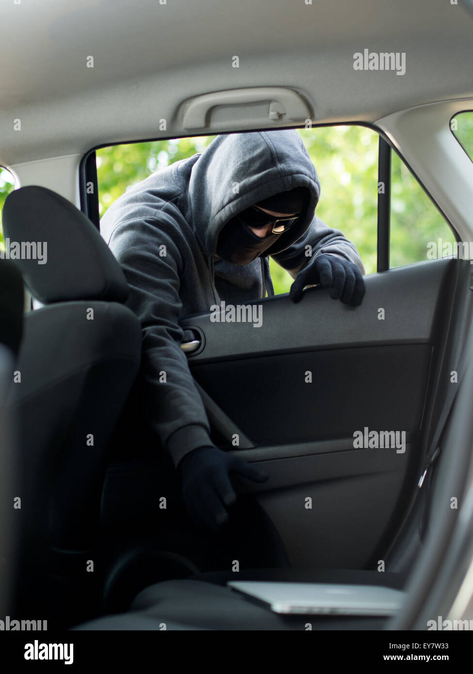 Car theft - a laptop being stolen through the window of an unoccupied car. Stock Photo