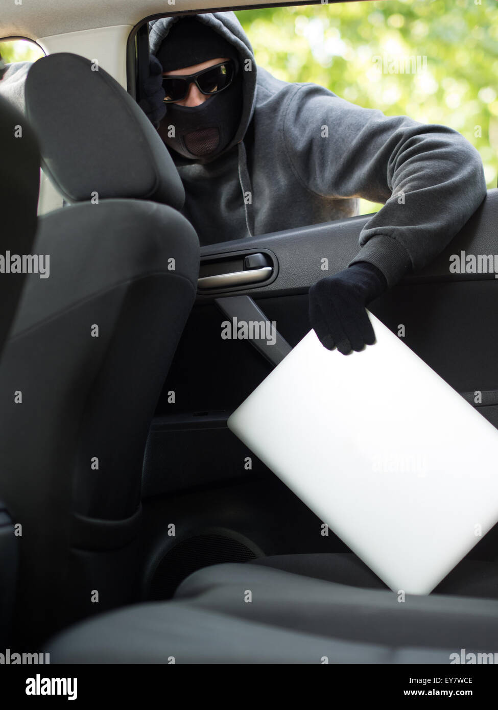 Car theft - a laptop being stolen through the window of an unoccupied car. Stock Photo