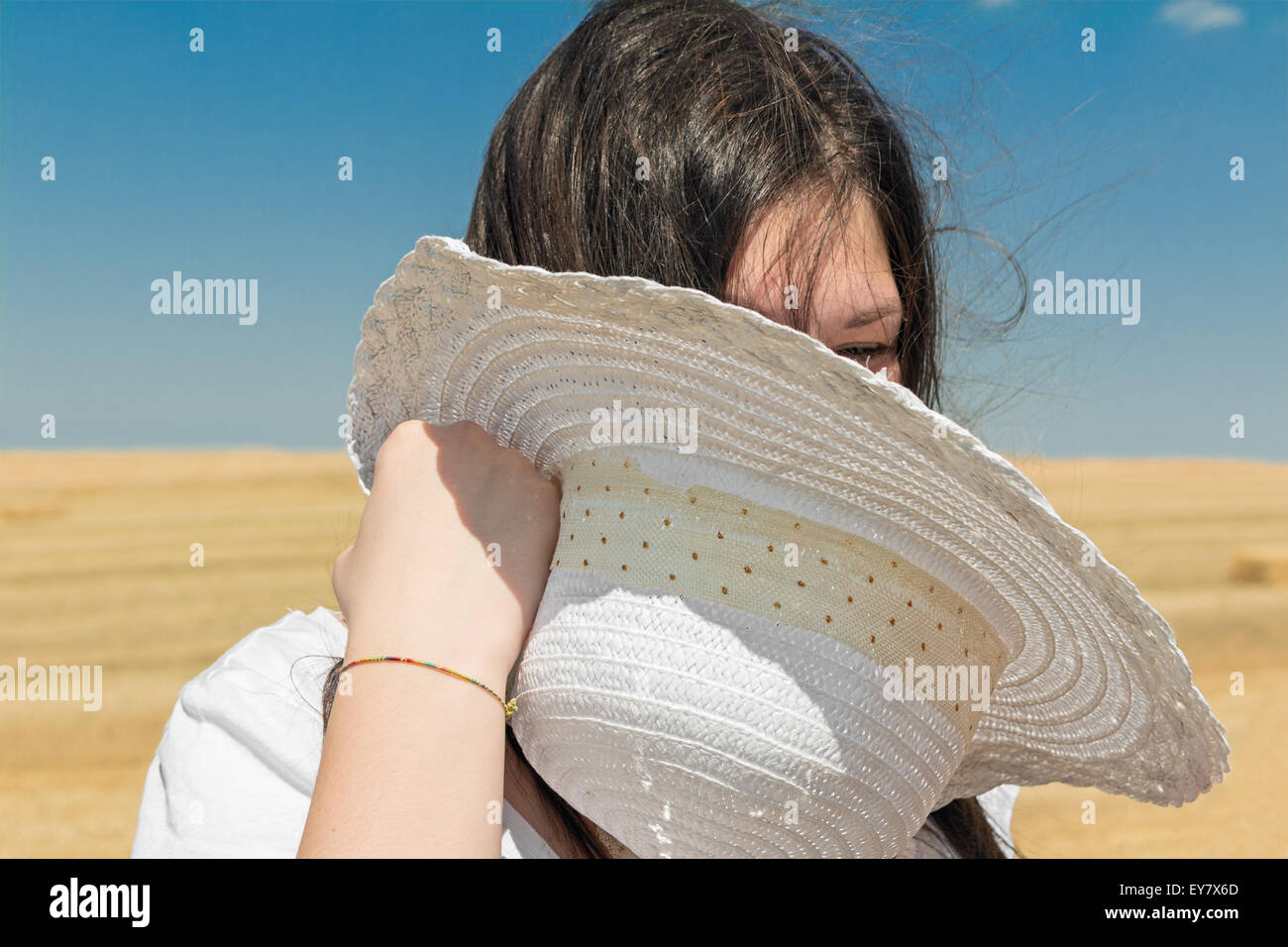 girl with white hat in hand in wheat field Stock Photo
