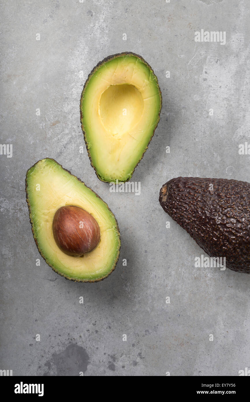 A Half and a whole Avocado on rustic metal background Stock Photo