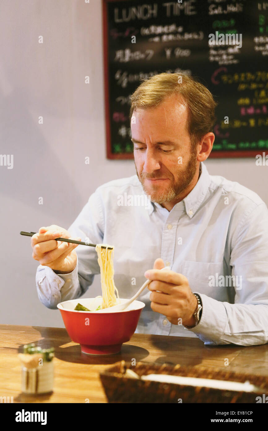 Caucasian man with beard eating ramen noodles Stock Photo