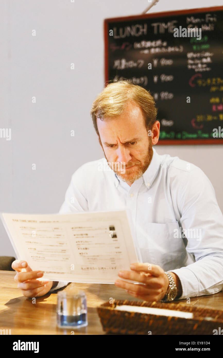 Caucasian man reading menu in a ramen restaurant Stock Photo