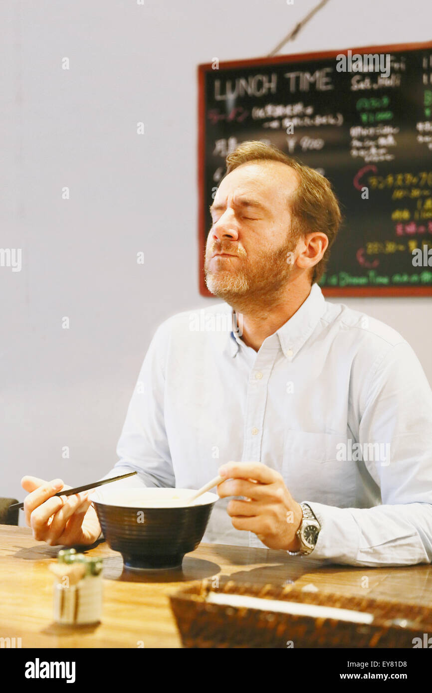 Caucasian man with beard eating ramen noodles Stock Photo