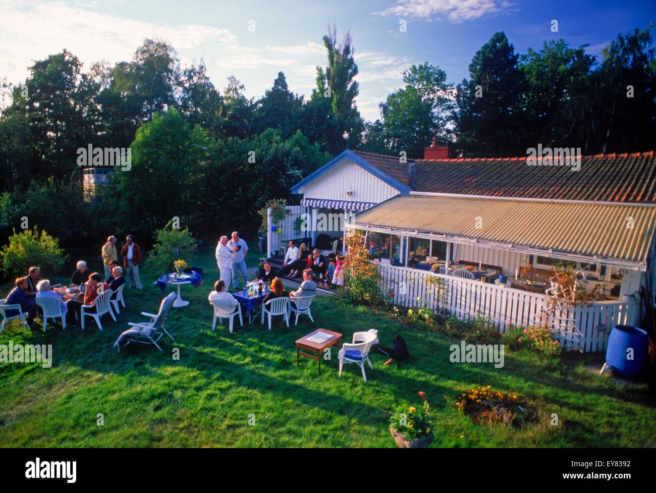 Friends sharing food, coffee and conversation at summer house on Tranholmen island in Stockholm Archipealgo in Baltic Sea waters Stock Photo