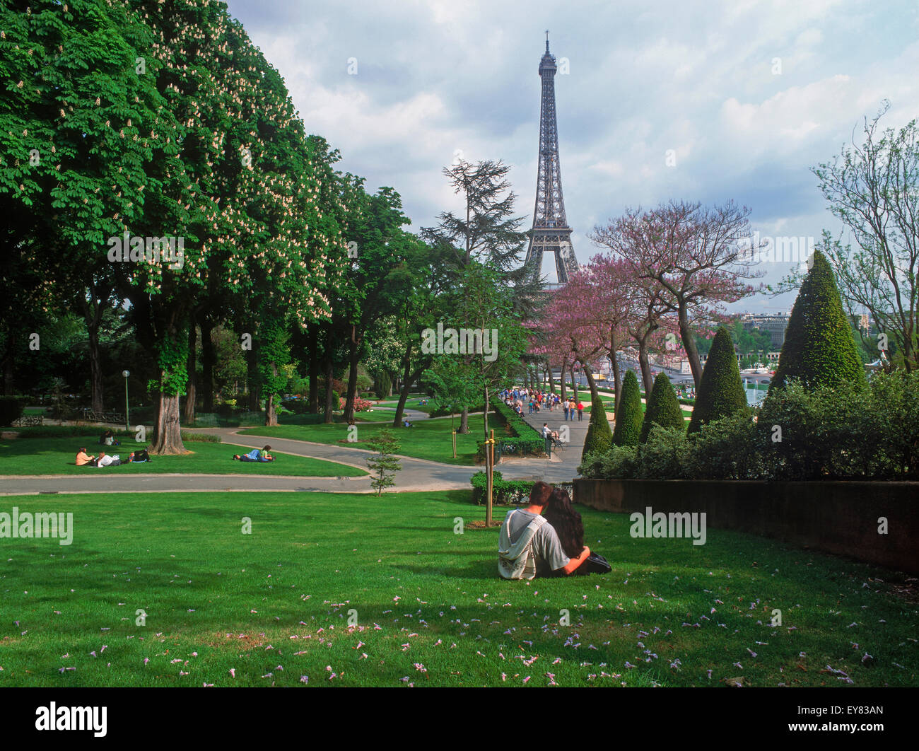 Couple sitting on lawn in Trocadero near Palais de Chaillot in Paris with Eiffel Tower Stock Photo