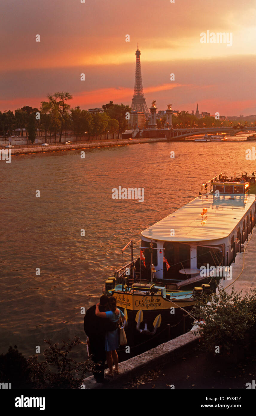 Couple near houseboats on River Seine in Paris at sunset with Eiffel Tower Stock Photo