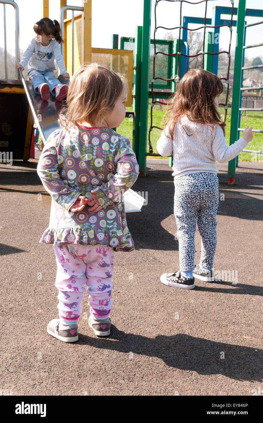 Toddlers in the playground with one girl holding her hands behind her back Stock Photo
