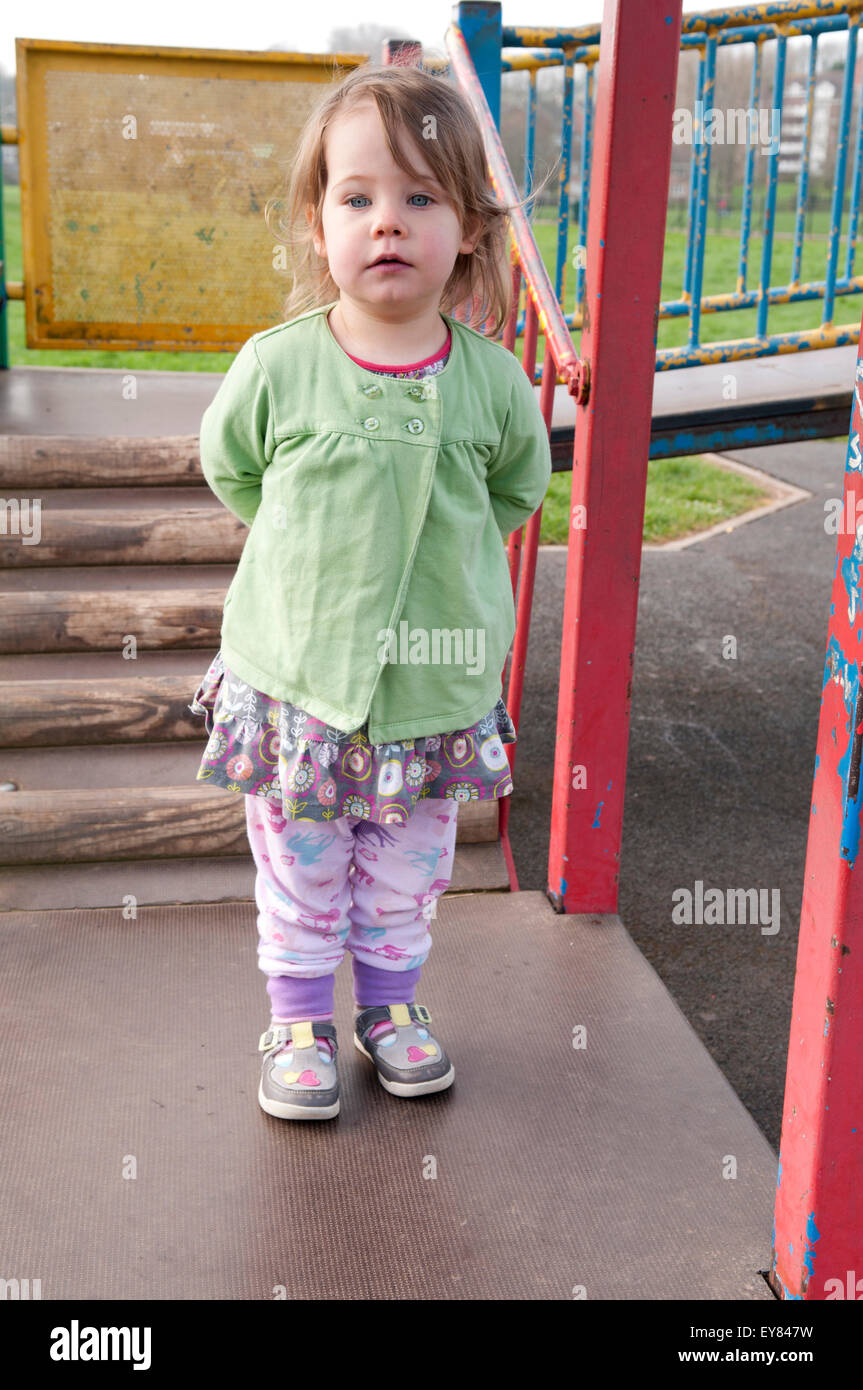 Little girl with her hands behind her back, looking pensive Stock Photo