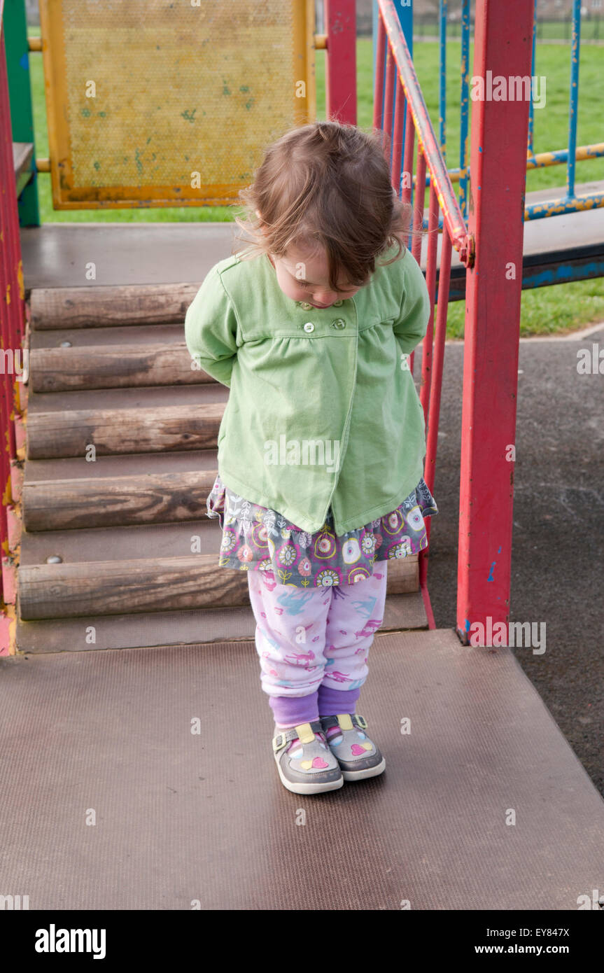 Little girl with her hands behind her back, looking down at her new shoes Stock Photo