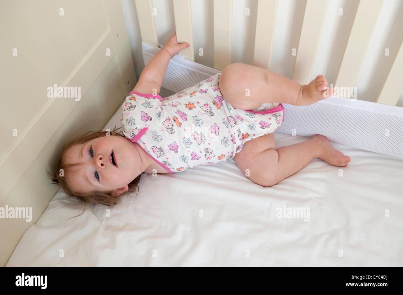 Overhead shot of baby girl lying down in her cot Stock Photo