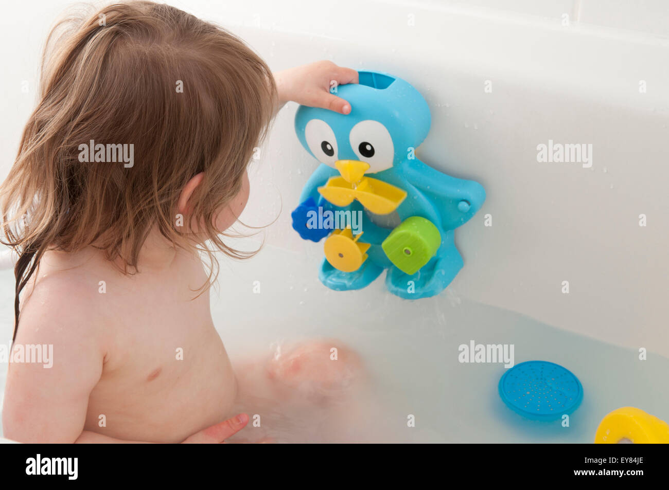 Toddler playing in the bath with bath toys Stock Photo