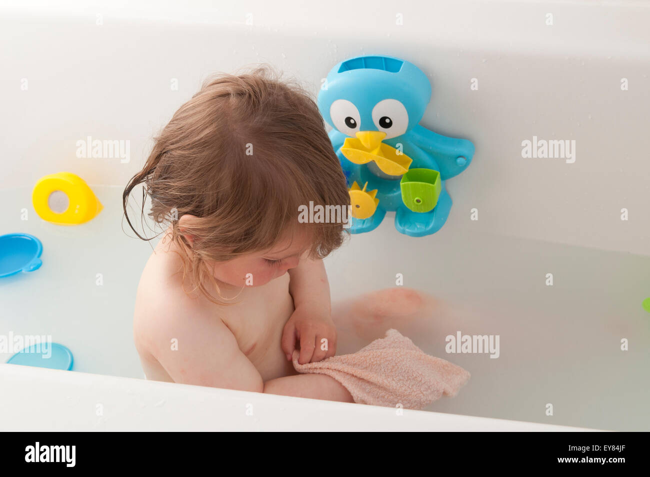 Toddler playing in the bath with bath toys and flannel Stock Photo Alamy