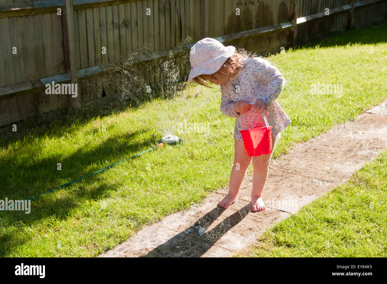 outside peeing girl child Little girl looking down at her wet feet from a garden sprinkler Stock  Photo - Alamy
