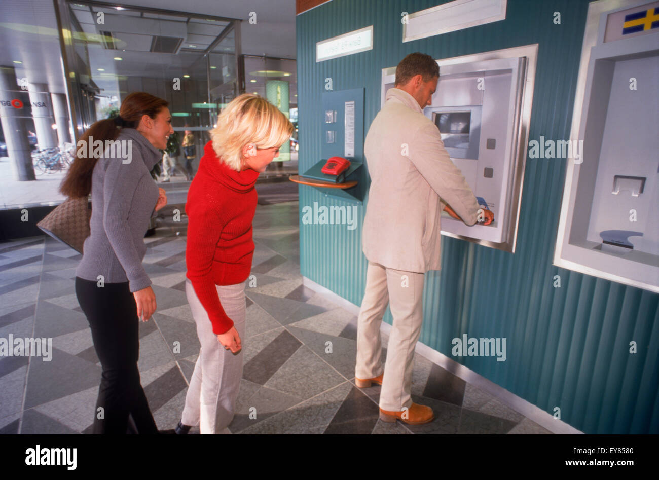 People waiting to use public bank ATM machines in Stockholm Stock Photo