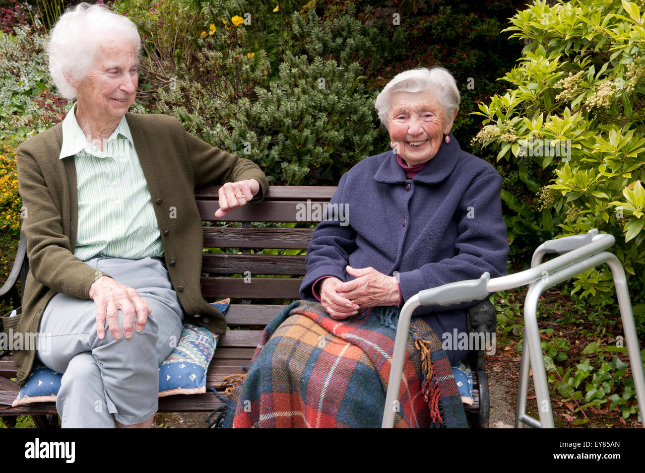 Portrait of two elderly women sitting on a garden bench smiling Stock ...