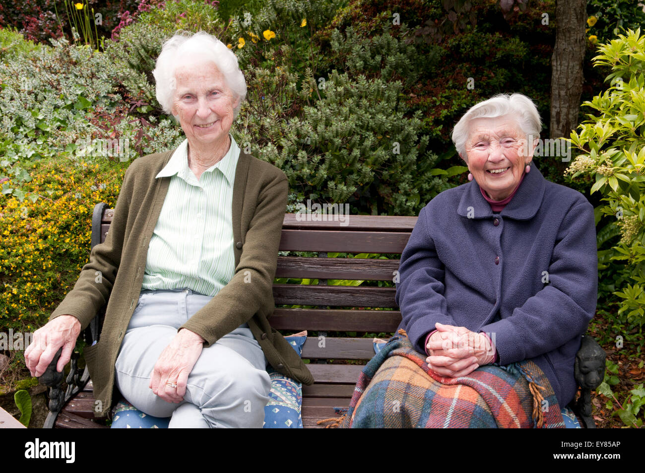 Portrait of two elderly women sitting on a garden bench smiling Stock ...