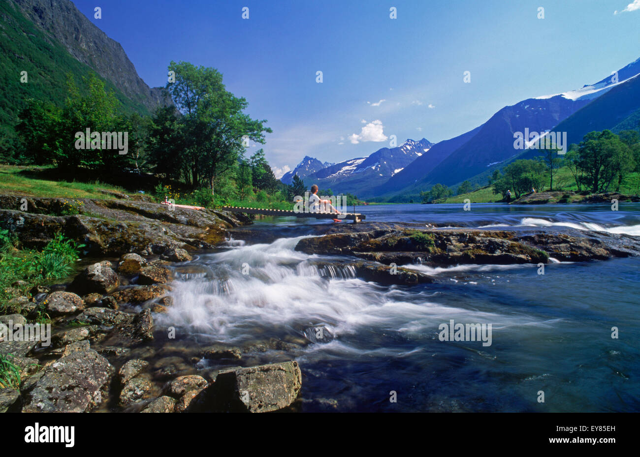 Woman resting next to Rauma River in Møre-Romsdal region of Norway ...