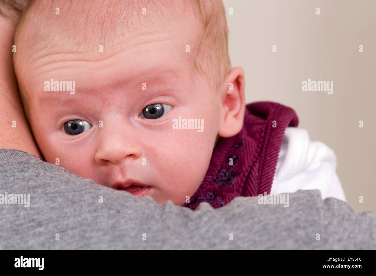 Newborn baby girl being held by her father, looking over his shoulder