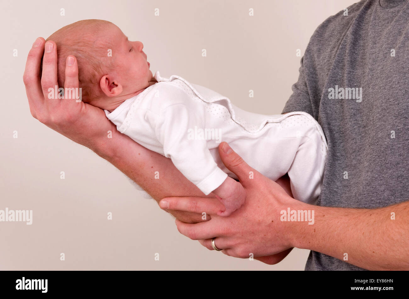 Close up shot of a newborn baby girl lying along her father's arm with