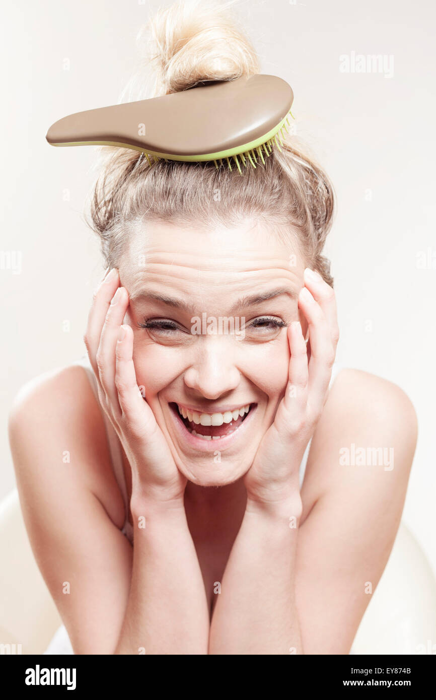 Young woman with hairbrush on head Stock Photo