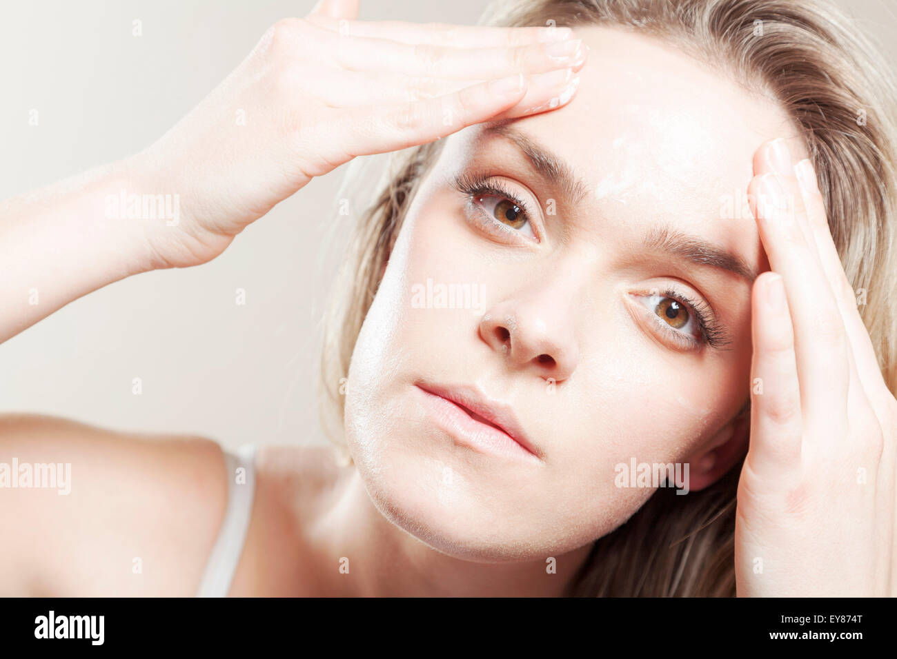 Young woman applying lotion on face, close-up Stock Photo