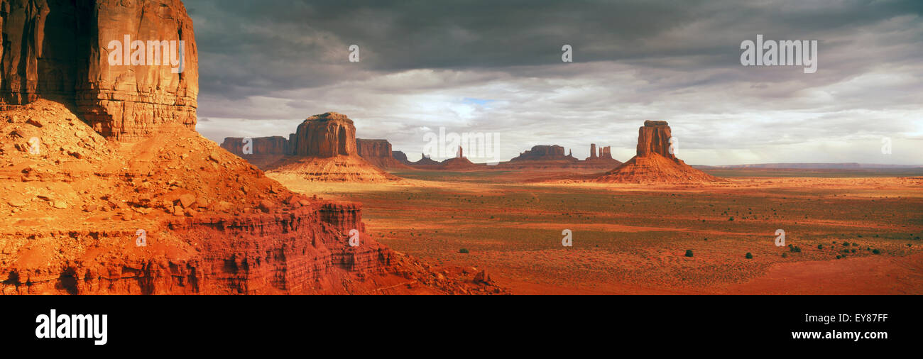 Panoramic shot of sunrise light moving across Monument Valley between passing clouds Stock Photo