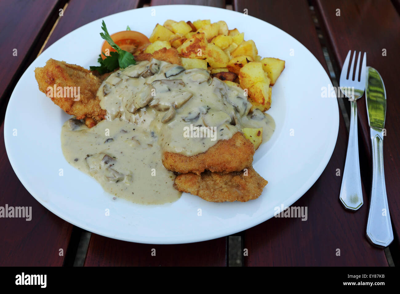 Mushroom sauce on a schnitzel served in Bad Homburg, Germany. The dish has a portion of Bratkertoffeln (fried potatoes). Stock Photo