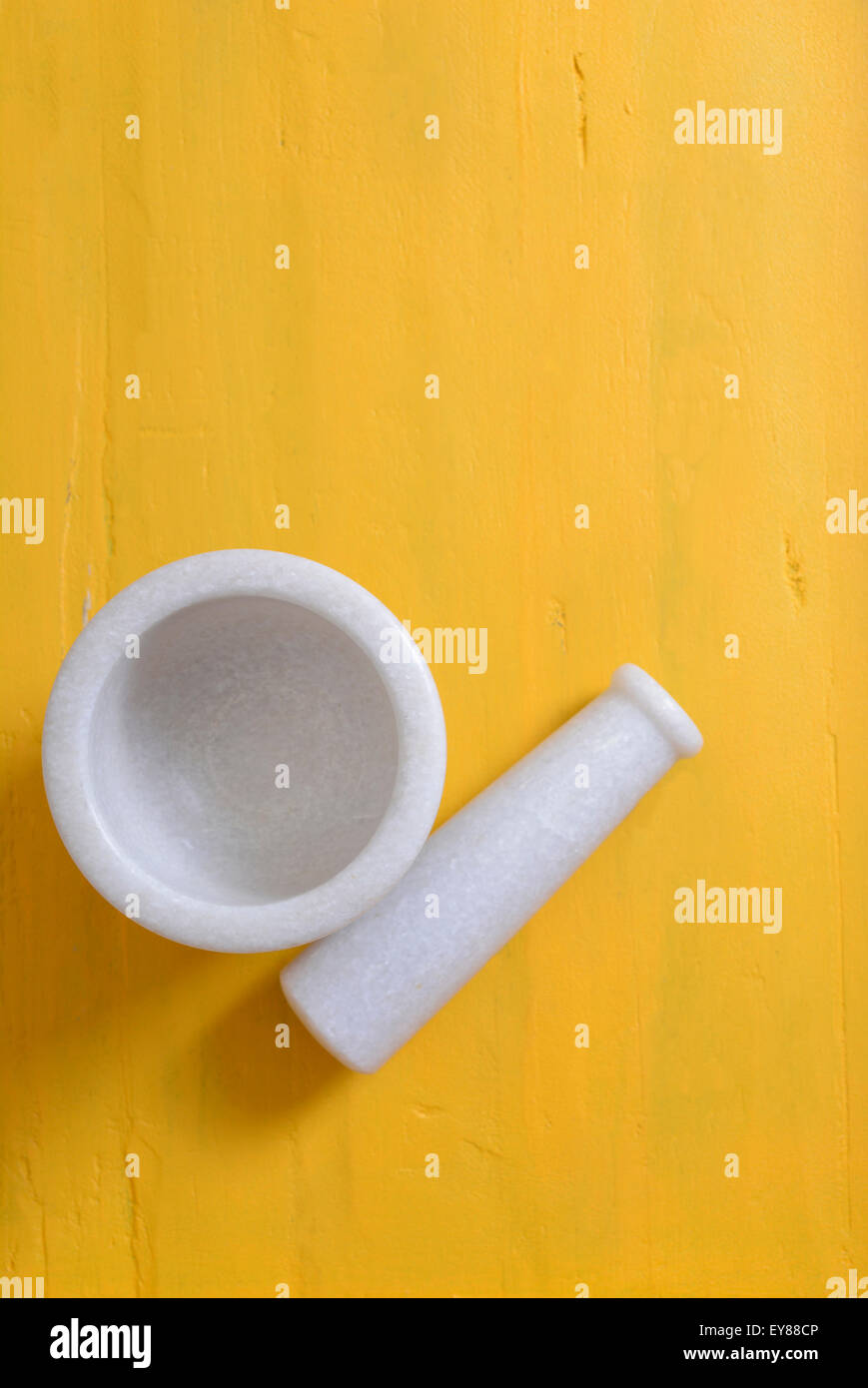 White marble mortar and pestle on vintage yellow wooden table with copy space for your text here. Stock Photo