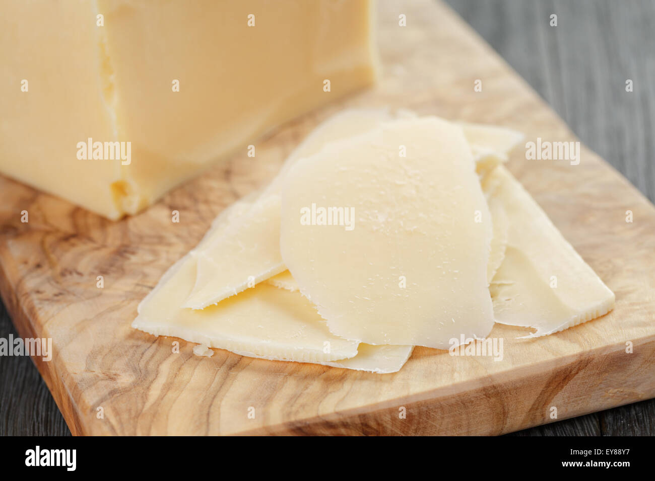 parmesan cheese sliced on olive board Stock Photo
