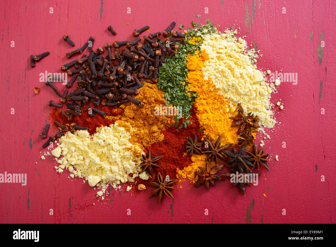 Colorful cooking spices and herbs on vintage red wood table. Stock Photo