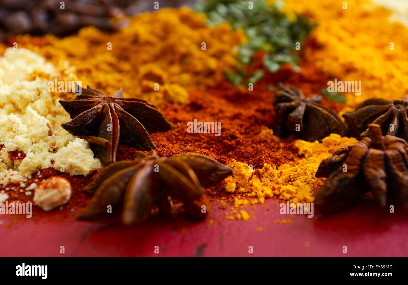 Colorful cooking spices and herbs on vintage red wood table with close up macro on star anise. Stock Photo