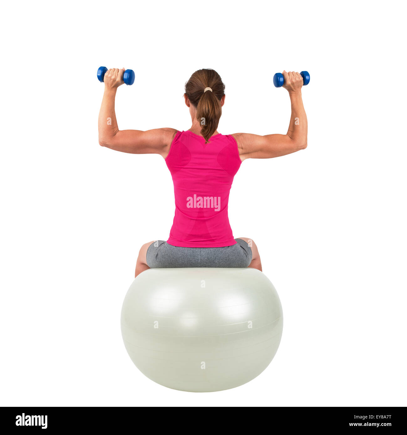 Sporty woman sitting on a gymnastic-ball and doing workout with barbells Stock Photo