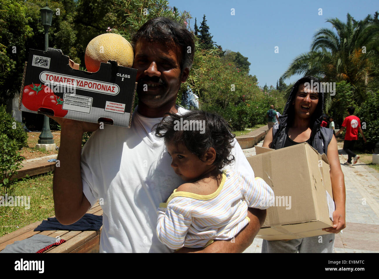 Athens, Greece. 24th July, 2015. Afghan refugees carry food back to their tent at a makeshift camp in a public park of Athens, Greece, July 24, 2015. Debt-stricken Greece struggles hard to cope with sharp rise in arrival of mainly Syrian and Afghan refugees fleeing war. It becomes increasingly difficult to provide them with proper housing facilities, food and medical assistance. Credit:  Marios Lolos/Xinhua/Alamy Live News Stock Photo
