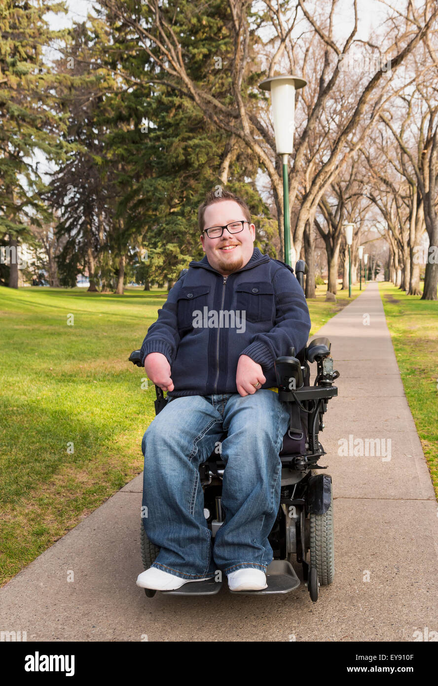 Disabled man using his powered wheelchair in a park in autumn; Edmonton, Alberta, Canada Stock