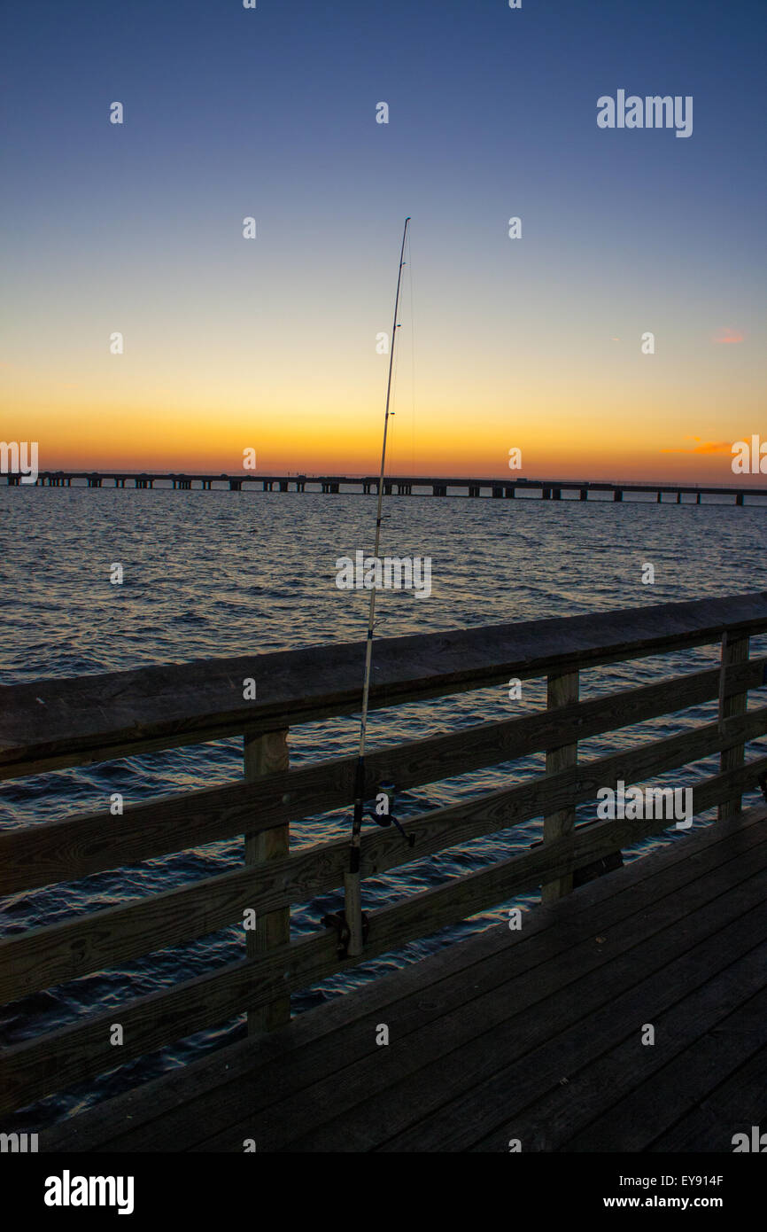 A fishing pole on a Lake Pontchartrain at Sunset.  The Lake Pontchartrain Causeway is in the distance Stock Photo