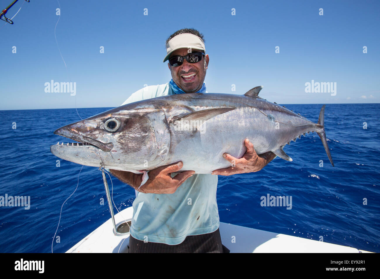 Fisherman holding a fresh caught Dogtooth Tuna (Gymnosarda unicolor); Tahiti Stock Photo