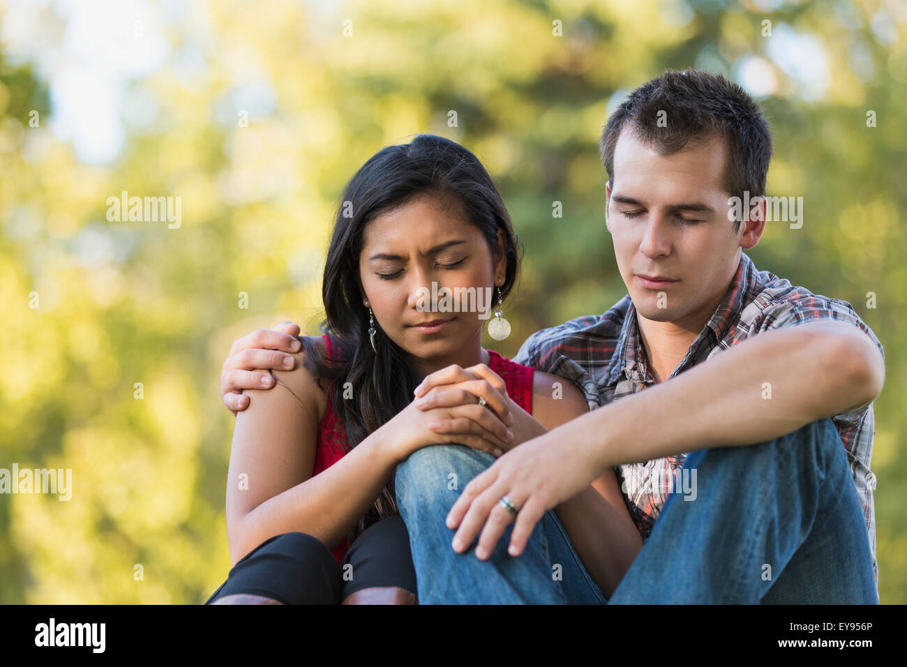 Mixed race couple praying together in a park in autumn; St. Albert, Alberta, Canada Stock Photo