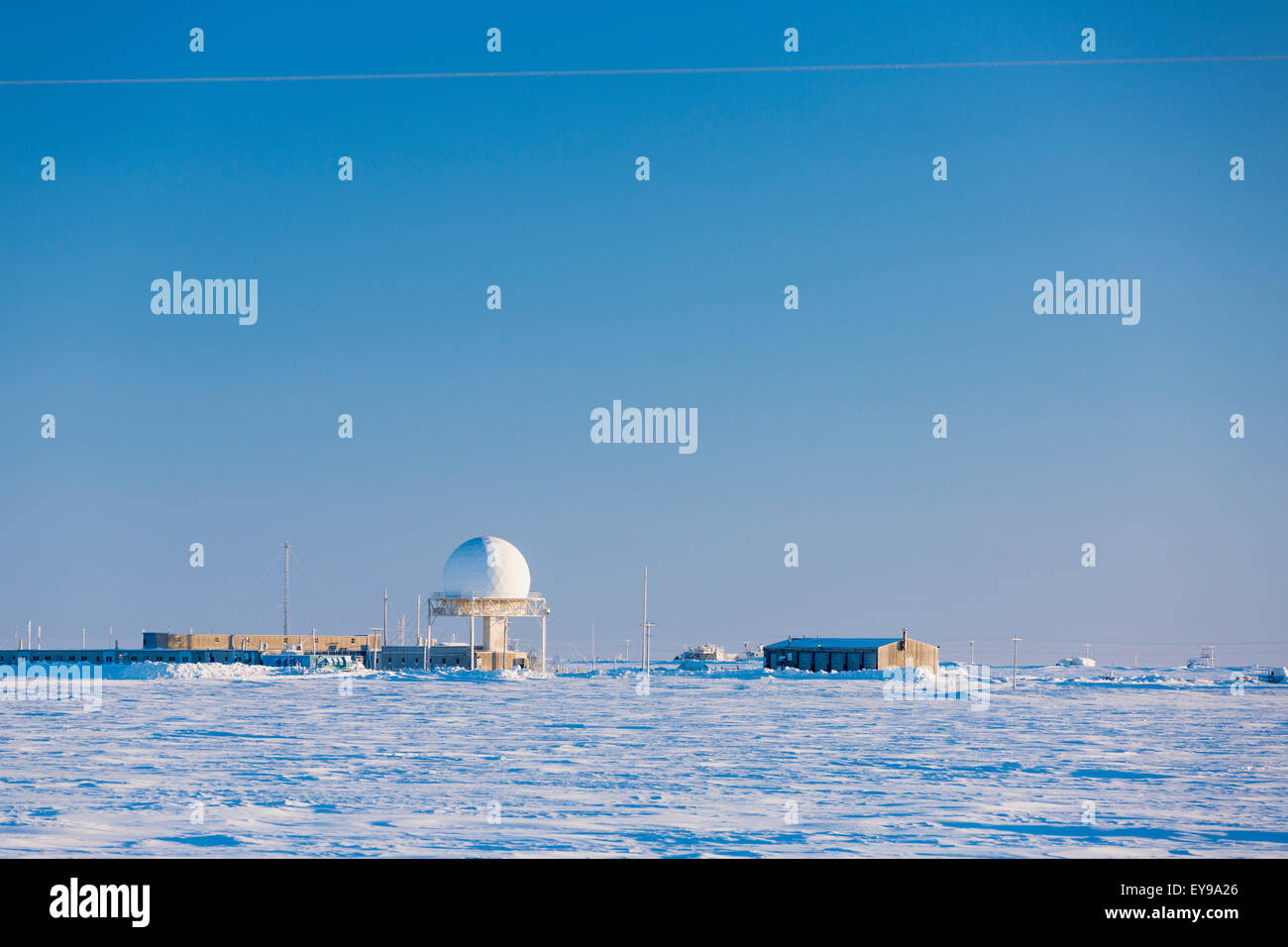 A radar dome and buildings of the Barrow naval base sit in a snowy