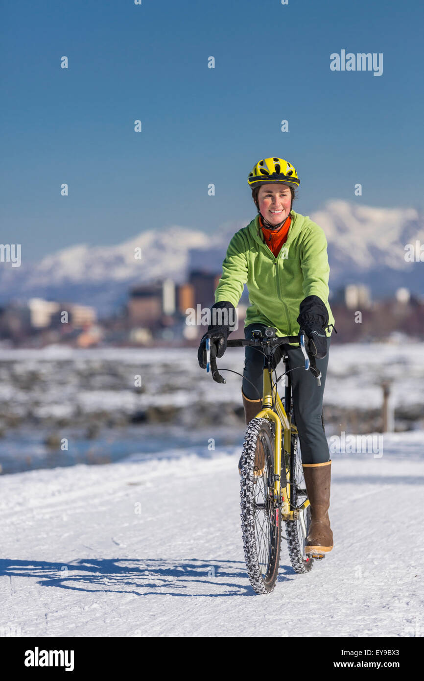 A Young Woman rides a studded tire bicycle down the Tony Knowles Coastal Trail, Anchorage, Southcentral Alaska, USA. Stock Photo