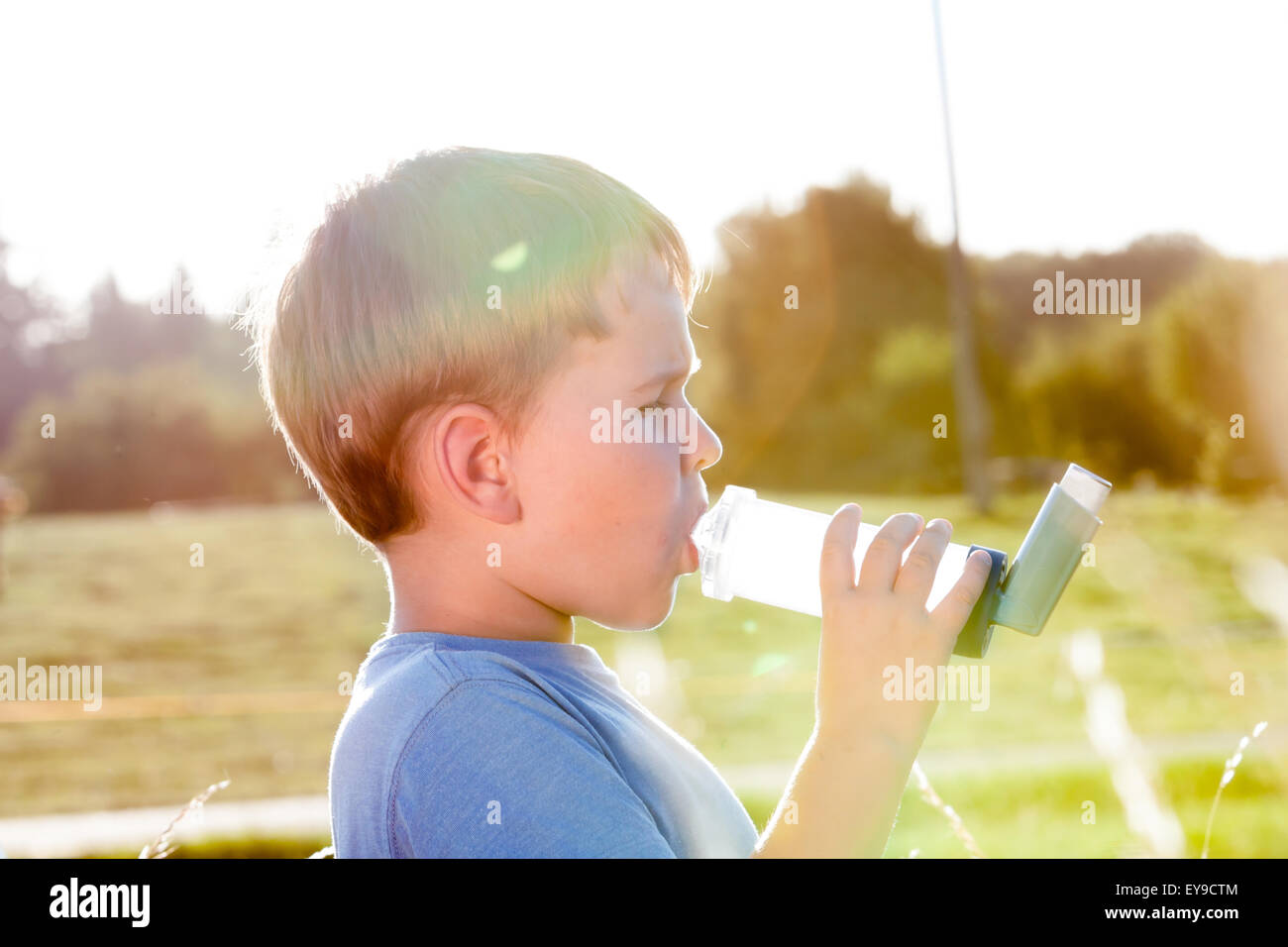 Boy using inhaler for asthma in village with summer sunset Stock Photo ...
